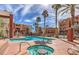 Community pool and hot tub surrounded by palm trees and lounge chairs on a sunny day at 55 E Agate Ave # 202, Las Vegas, NV 89123