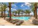Sparkling community pool with inviting lounge chairs surrounded by swaying palm trees and blue skies at 58 Sun Lily Ln, Henderson, NV 89011
