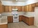 Functional kitchen featuring wood cabinets, white appliances and a tile floor at 6416 Pronghorn Ridge Ave, Las Vegas, NV 89122