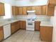Well-lit kitchen with wood cabinets, white appliances and durable tile floors at 6416 Pronghorn Ridge Ave, Las Vegas, NV 89122