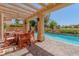 A covered patio features a dining table with seating, stone floor and view of the pool at 7625 Spanish Bay Dr, Las Vegas, NV 89113