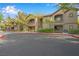 Tan condo building with balconies and stairways framed by lush green trees against a vibrant blue sky at 8250 N Grand Canyon Dr # 1123, Las Vegas, NV 89166