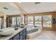 Bright bathroom with double sink vanity, granite countertops, and a large soaking tub by the window at 8320 Opal Cove Dr, Las Vegas, NV 89128