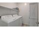 Laundry room provides a white washer and dryer set, storage cabinet, and floating shelf at 8898 Sasquatch Run Ave, Las Vegas, NV 89166