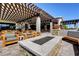 Relaxing outdoor patio featuring a fire pit, comfortable seating, and pergola offering shade and style at 8898 Sasquatch Run Ave, Las Vegas, NV 89166