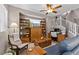 Cozy living room featuring a ceiling fan, bookshelves, comfortable seating, and stairs leading to the upper level at 9218 Grassy Weep Ct, Las Vegas, NV 89178