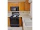 Bright kitchen featuring wooden cabinets, white countertop and a stainless steel faucet near a modern black range and microwave at 9312 Yucca Blossom Dr, Las Vegas, NV 89134