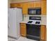 This cozy kitchen has wooden cabinets, a white refrigerator and a modern black range with a built-in microwave above at 9312 Yucca Blossom Dr, Las Vegas, NV 89134