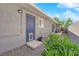 View of a backyard with a blue door, gravel landscaping and green bushes against a wall at 942 Westminster Ave, Las Vegas, NV 89119