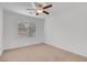 A spacious, empty bedroom featuring neutral walls, neutral carpeting, a ceiling fan, and natural light at 10410 Poplar Park Ave, Las Vegas, NV 89166