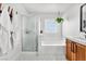 Bright bathroom features a soaking tub, glass-enclosed shower, and white and wood vanity at 10432 Britton Hill Ave, Las Vegas, NV 89129