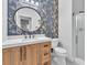 Bathroom featuring an ornate mirror, decorative wallpaper, and wood vanity with a shower to the right at 10432 Britton Hill Ave, Las Vegas, NV 89129