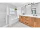 Bright bathroom featuring a walk-in shower, soaking tub and dual sinks with a wood vanity at 10432 Britton Hill Ave, Las Vegas, NV 89129