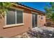 Back patio area with a sliding glass door, small windows, and neutral stucco, leading to a stone-paved outdoor space at 1139 Via Partito, Henderson, NV 89052