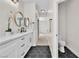 Bathroom with double sink vanity, round mirrors, hexagon tile flooring, and adjacent toilet room at 1551 Boundary Peak Way, Las Vegas, NV 89135