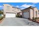 Exterior view of a stucco home with a three car garage and a well-manicured front yard at 1551 Boundary Peak Way, Las Vegas, NV 89135
