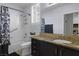 Bathroom featuring granite vanity, tub, and shower with patterned curtain and plantation shutters at 1777 Antelope Valley Ave, Henderson, NV 89012