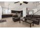 Spacious living room with dark furniture, ceiling fan, and tile flooring flowing into the kitchen at 1777 Antelope Valley Ave, Henderson, NV 89012