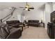 Cozy living room with plush leather sofas, a ceiling fan, and staircase views at 1777 Antelope Valley Ave, Henderson, NV 89012