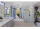 Bright bathroom featuring a soaking tub and separate glass shower with gray cabinets and marble-look tile at 3 Chatmoss Rd, Henderson, NV 89052