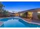Backyard at dusk featuring a pool, patio furniture, tropical landscaping and a brick patio at 3 Chatmoss Rd, Henderson, NV 89052