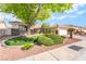 Landscaped front yard featuring green grass, mature tree, and rock garden at 3436 Camsore Point Ln, Las Vegas, NV 89129