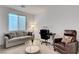 Bright living room area featuring a sofa, large window, desk with chair, and accent chair at 4177 Railhead Pass Ave, Las Vegas, NV 89141