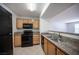 Classic kitchen with wood cabinets, granite countertops, and modern black appliances at 5055 W Hacienda Ave # 2125, Las Vegas, NV 89118