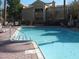 Community pool with lounge chairs, tables, and a view of the surrounding buildings and landscaping at 8139 Retriever Ave, Las Vegas, NV 89147