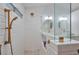 Modern bathroom featuring a tiled shower, glass partition, dual sinks, and round mirrors with gold fixtures at 8404 Shore Breeze Dr, Las Vegas, NV 89128