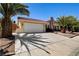 Single-story home with a two-car garage, landscaped yard, and mature palm trees at 8705 Orvieto Dr, Las Vegas, NV 89117