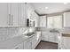 White kitchen with quartz countertops, stainless appliances, tile backsplash, and white shuttered window at 8797 Pinley Spring St, Las Vegas, NV 89113