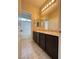 Bathroom featuring double sink vanity with dark wood cabinets, granite countertops, and white tile shower and flooring at 9138 Hermosa Valley St, Las Vegas, NV 89178
