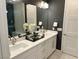 Bathroom featuring dual sinks, white cabinets, a decorative mirror, and a glass-enclosed shower at 929 Hunter Shores Ave, North Las Vegas, NV 89084