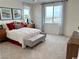 Bright bedroom features a large window, neutral carpet, a bed with red accents, and contemporary art at 929 Hunter Shores Ave, North Las Vegas, NV 89084