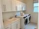 Clean and efficient laundry room includes a sink, countertop space, storage cabinets, and modern washer and dryer at 929 Hunter Shores Ave, North Las Vegas, NV 89084