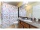 Well-lit bathroom with a floral shower curtain, single vanity, and plenty of space for toiletries at 9823 Belle Marie Ct, Las Vegas, NV 89141