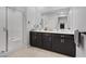 Elegant bathroom featuring double sinks with sleek dark cabinetry, framed mirror and glass enclosed shower at 143 Aqua Commons Ln, Henderson, NV 89015