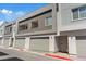Close-up of townhouses featuring two-car garages, neutral exterior and small balcony at 143 Aqua Commons Ln, Henderson, NV 89015