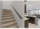 Carpeted staircase ascending to the main living area with modern railing and kitchen view at 143 Aqua Commons Ln, Henderson, NV 89015
