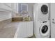 Well-lit laundry room with white cabinets, stacked washer and dryer at 204 Appian Way, Henderson, NV 89002