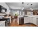 Spacious open kitchen and dining area with stainless appliances, white cabinets, and hardwood flooring at 2078 Wildwood Lake St, Henderson, NV 89052