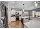Open concept kitchen featuring stainless appliances, white cabinets, stone countertops, and hardwood flooring at 2078 Wildwood Lake St, Henderson, NV 89052