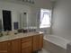 Bright bathroom with double sinks, a soaking tub, and tiled accents, offering a spa-like experience at 2148 Hidden Ranch Ter, Henderson, NV 89052