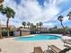 Community pool surrounded by palm trees and lounge chairs under a partly cloudy sky at 2295 Koho Dr # 102, Las Vegas, NV 89183