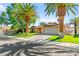 Charming home featuring palm trees, lush green lawn, and a well-maintained two-car garage at 2426 La Pluma St, Henderson, NV 89014
