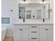 Bathroom view featuring a double sink vanity, black fixtures, and a large mirror with decorative lighting at 2894 Matese Dr, Henderson, NV 89052