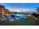 Tranquil pool and patio area with comfortable lounge chairs overlooking a sunset view with city lights at 2901 Josephine Dr, Henderson, NV 89044