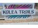 Kalea Trails community sign with pink and turquoise accents, near a gravel bed and mountain view at 6104 Aster Garden St # 129, North Las Vegas, NV 89081