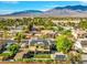 A sunny aerial view of the property showcasing its solar panels and the surrounding neighborhood with mountain views at 6335 Iginlas Goal Ave, Las Vegas, NV 89131